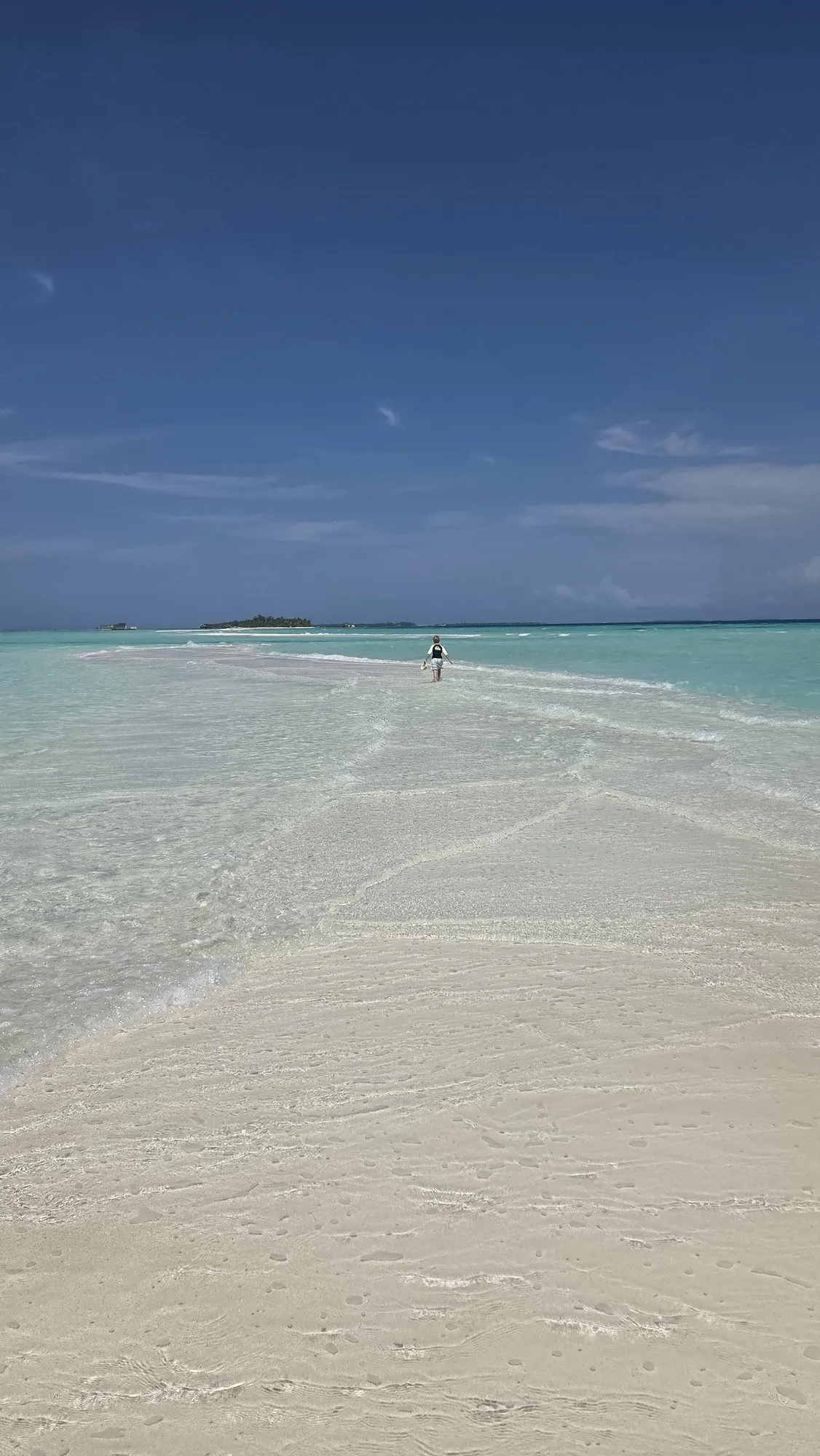 Die lange helle Sandbank von Dhigurah zieht sich ins türkise Flachwasser, am Ende steht eine einzelne Person.