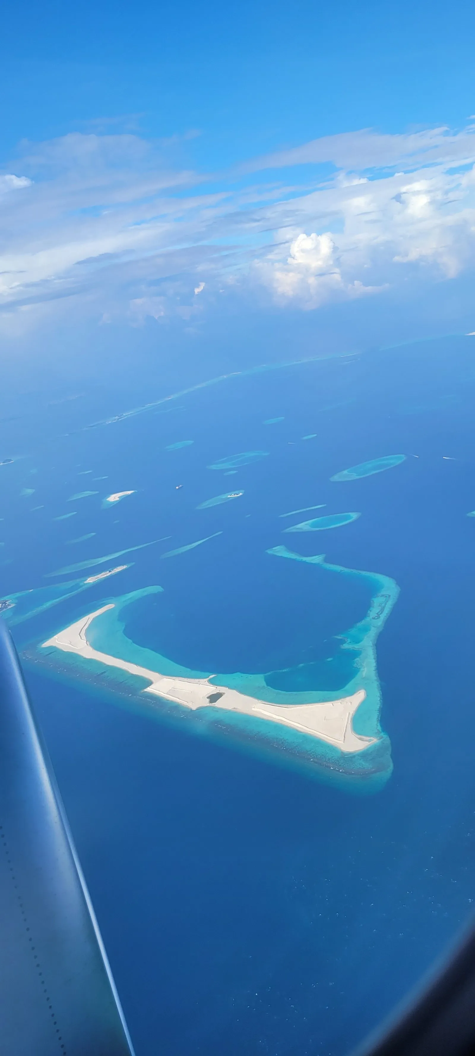 Blick über ein Atoll der Malediven, flaches türkises Wasser über hellem Sand.